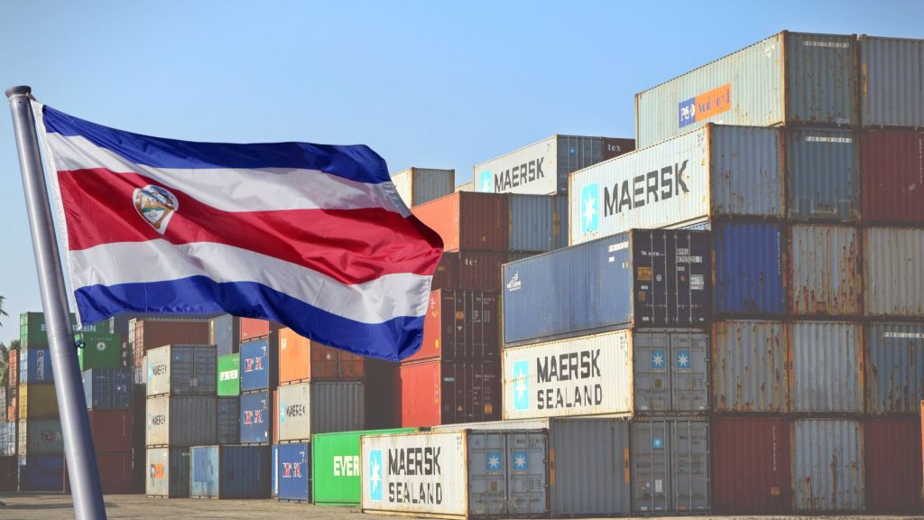 Bandera de Costa Rica frente a pilas de contenedores marítimos; comercio exterior