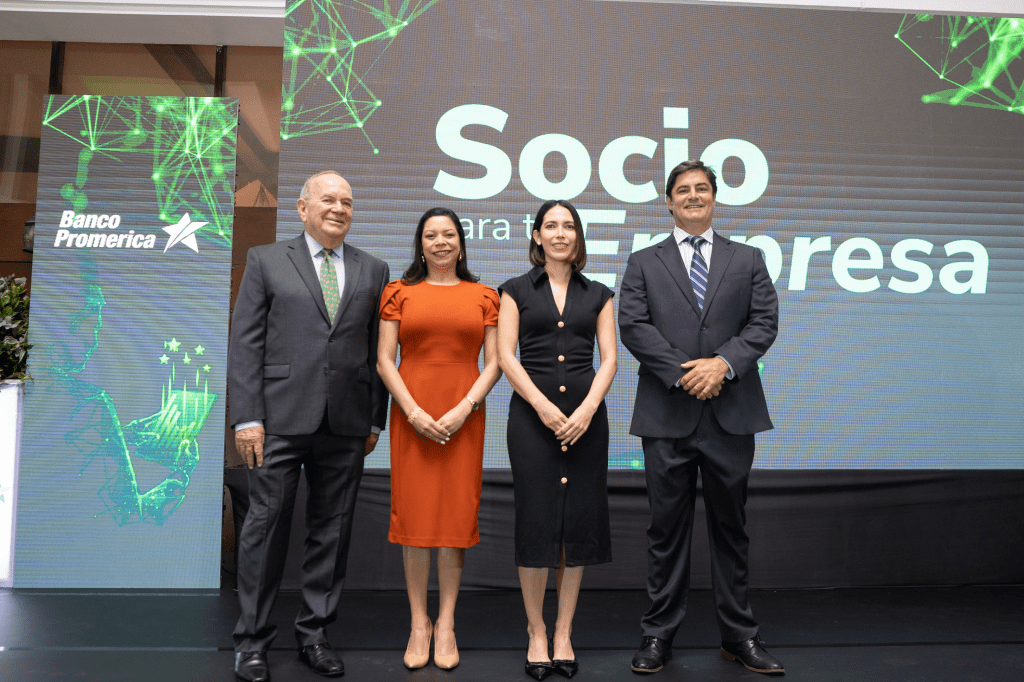 Cuatro personas posando juntas frente a un fondo con el logo de Banco Promerica, que presenta un mensaje sobre ser socio para la empresa.